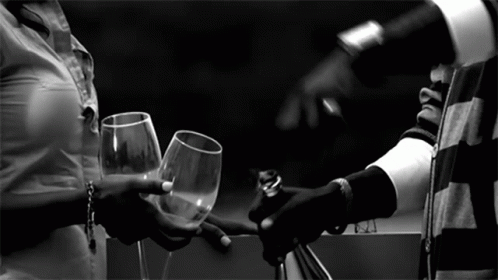 A Black And White Photo Of A Woman Holding A Glass Of Wine GIF