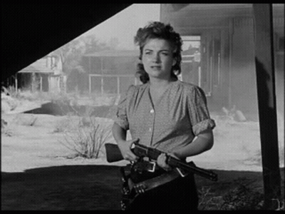 A Black And White Photo Of A Woman Holding A Gun In Her Hand . GIF