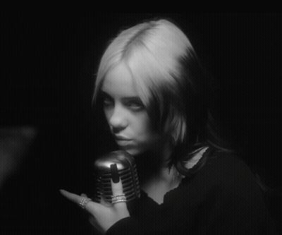 A Black And White Photo Of A Woman Holding A Microphone In Her Hand GIF