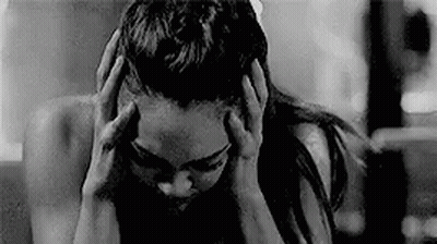 A Black And White Photo Of A Woman Holding Her Head In Pain . GIF