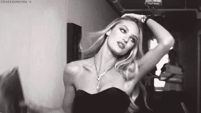 A Black And White Photo Of A Woman In A Black Dress And Necklace . GIF