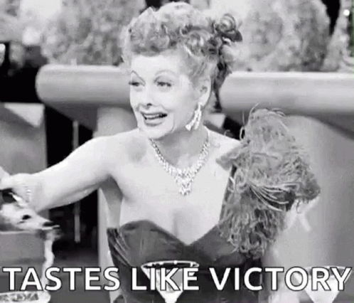A Black And White Photo Of A Woman In A Dress Holding A Glass Of Wine And Saying `` Tastes Like Victory '' . GIF