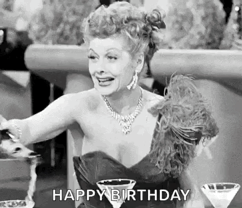 A Black And White Photo Of A Woman In A Dress Holding A Martini Glass And Saying `` Happy Birthday '' . GIF