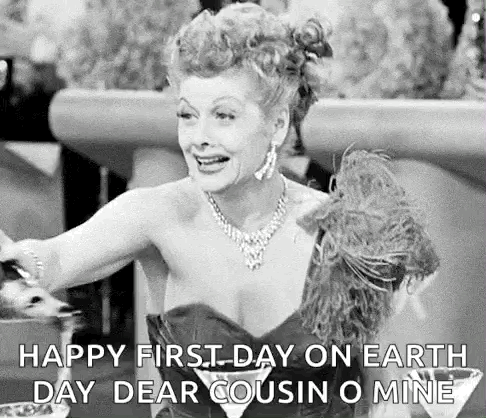 A Black And White Photo Of A Woman In A Dress Sitting At A Table With A Martini In Her Hand . GIF