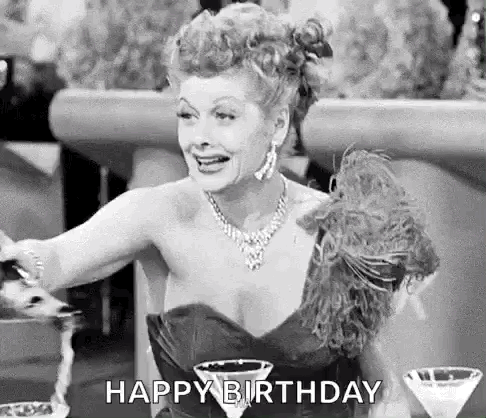 A Black And White Photo Of A Woman In A Dress Sitting At A Table With Martini Glasses And Saying Happy Birthday . GIF