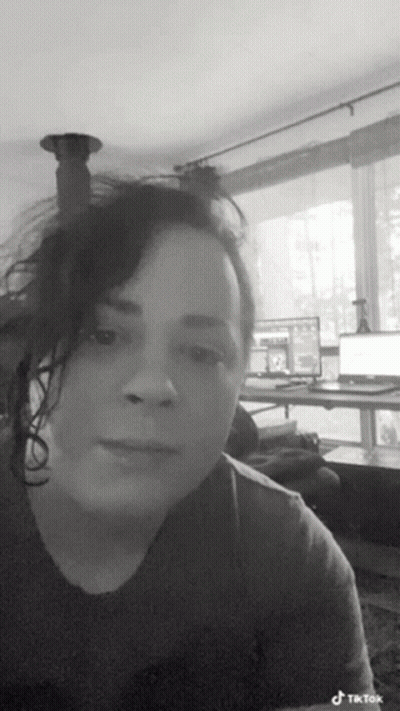 A Black And White Photo Of A Woman In A Living Room With A Laptop On A Desk . GIF