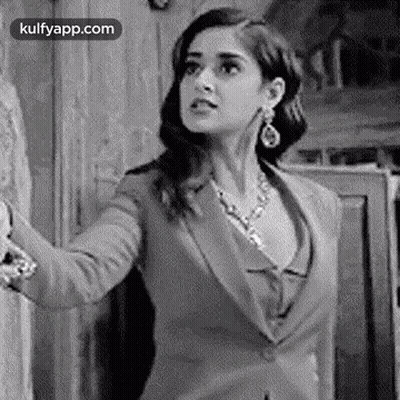 A Black And White Photo Of A Woman In A Suit And A Necklace . GIF