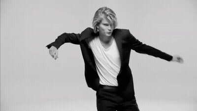 A Black And White Photo Of A Woman In A Suit Holding Her Hand To Her Chin . GIF