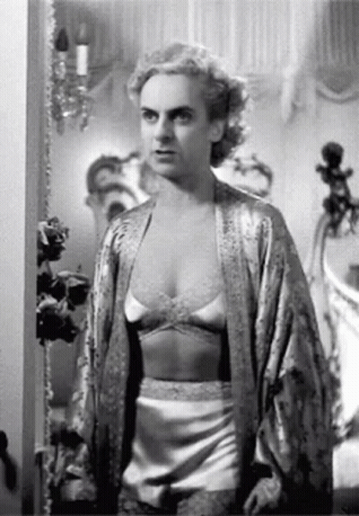 A Black And White Photo Of A Woman In Lingerie And A Robe Standing In A Room . GIF