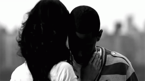 A Black And White Photo Of A Woman Kissing A Man 'S Forehead . GIF