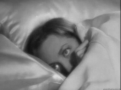 A Black And White Photo Of A Woman Laying In Bed With Her Eyes Open . GIF