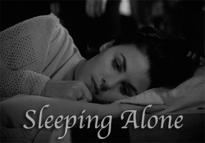 A Black And White Photo Of A Woman Laying In Bed With The Words Sleeping Alone Above Her GIF