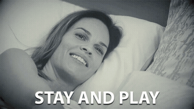 a black and white photo of a woman laying on a bed with the caption stay and play