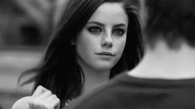 A Black And White Photo Of A Woman Looking At A Man In A Park . GIF