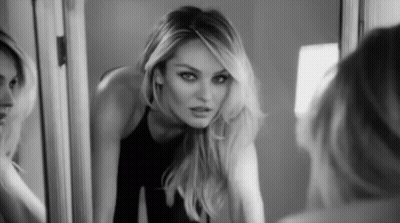 A Black And White Photo Of A Woman Looking At Her Reflection In A Mirror GIF