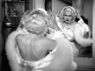 A Black And White Photo Of A Woman Looking At Herself In The Mirror . GIF