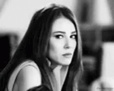 A Black And White Photo Of A Woman Looking At The Camera . GIF