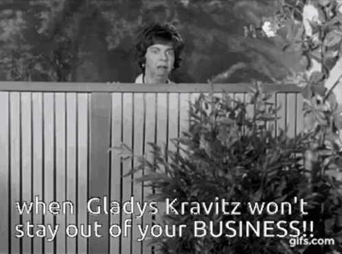 A Black And White Photo Of A Woman Peeking Over A Wooden Fence With A Quote . GIF
