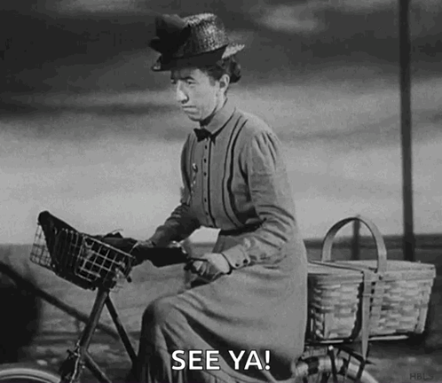 A Black And White Photo Of A Woman Riding A Bicycle With A Basket And The Words `` See Ya '' . GIF