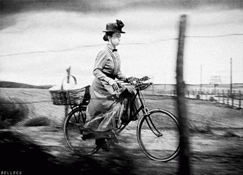 A Black And White Photo Of A Woman Riding A Bicycle With Bellecs Written On The Bottom GIF