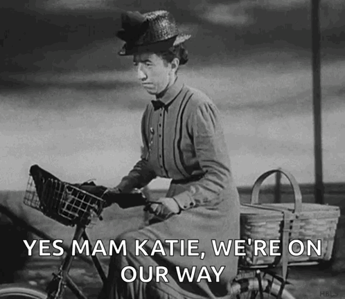 A Black And White Photo Of A Woman Riding A Bike With The Words Yes Mam Katie We 'Re On Our Way GIF