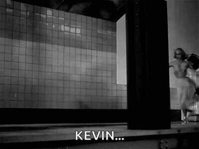 A Black And White Photo Of A Woman Running In A Room With The Word Kevin In The Corner GIF