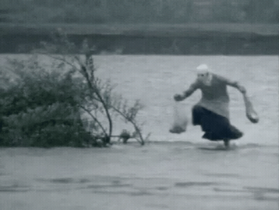 A Black And White Photo Of A Woman Running Through A Flooded Area . GIF