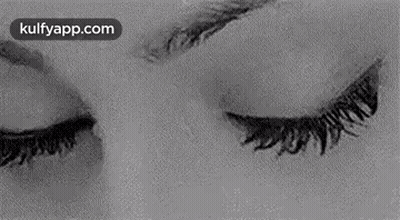 A Black And White Photo Of A Woman 'S Eyes Looking At The Camera . GIF
