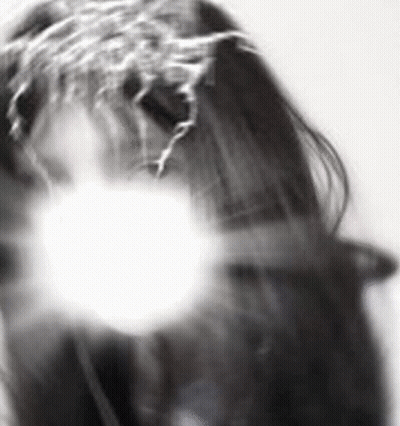 A Black And White Photo Of A Woman 'S Face With A White Light Behind Her . GIF