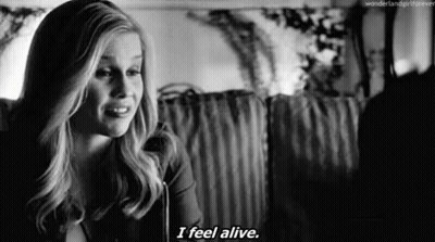 A Black And White Photo Of A Woman Saying `` I Feel Alive '' While Sitting On A Couch . GIF