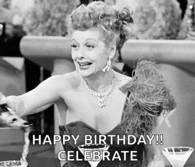 A Black And White Photo Of A Woman Sitting At A Table With A Martini Glass And A Feather Boa . GIF