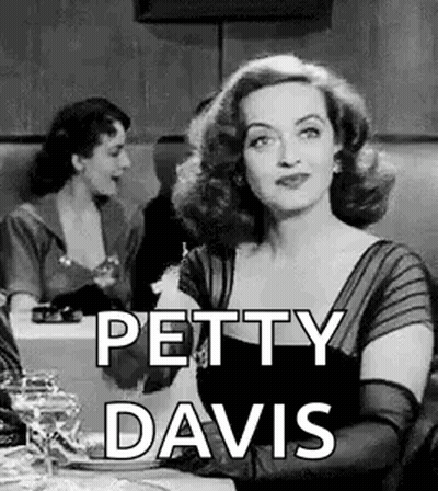 A Black And White Photo Of A Woman Sitting At A Table With The Words `` Petty Davis '' . GIF