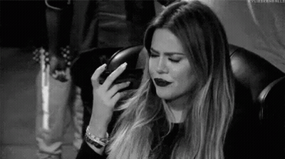 A Black And White Photo Of A Woman Sitting In A Chair With Her Hand On Her Face . GIF