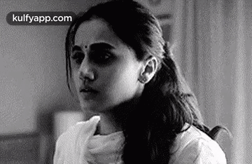 A Black And White Photo Of A Woman Sitting In A Chair With Her Hand On Her Neck . GIF