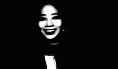 A Black And White Photo Of A Woman Smiling In The Dark GIF