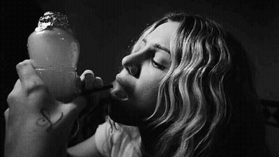 A Black And White Photo Of A Woman Smoking A Hookah GIF