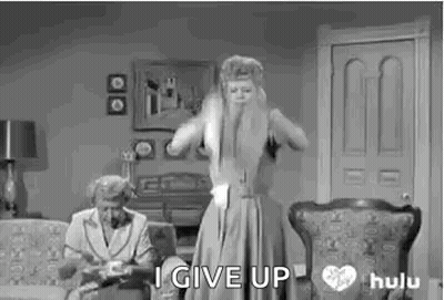 A Black And White Photo Of A Woman Standing In A Living Room With A Woman Sitting On A Couch Behind Her . GIF