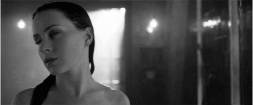A Black And White Photo Of A Woman Standing In A Shower . GIF