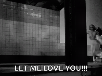 A Black And White Photo Of A Woman Standing In Front Of A Building . GIF