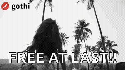 A Black And White Photo Of A Woman Standing In Front Of Palm Trees And The Words `` Free At Last ! '' GIF