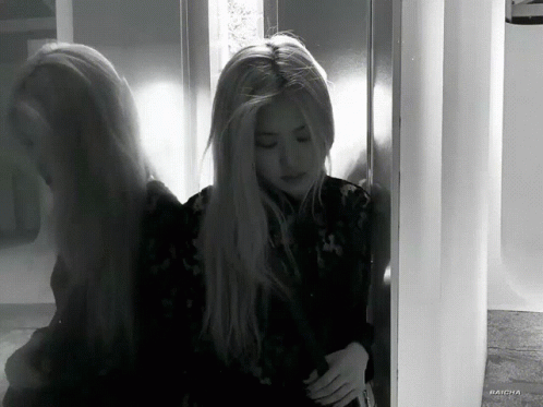A Black And White Photo Of A Woman Standing Next To A Door GIF