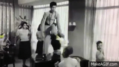 A Black And White Photo Of A Woman Standing On A Chair In A Living Room . GIF