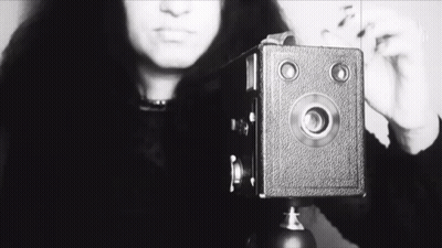 A Black And White Photo Of A Woman Taking A Picture With The Word She Visible GIF