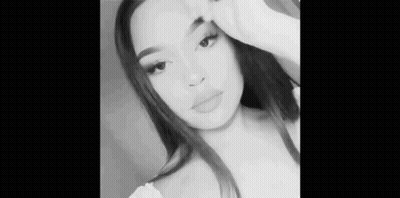 A Black And White Photo Of A Woman Taking A Selfie With Her Hand On Her Face . GIF