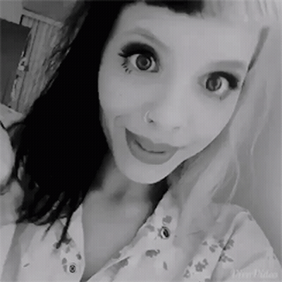 A Black And White Photo Of A Woman Taking A Selfie With Her Nose Ring . GIF