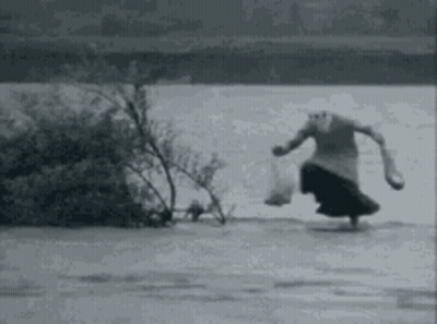 A Black And White Photo Of A Woman Walking On A Frozen Lake . GIF