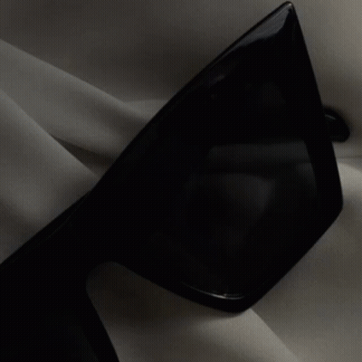 A Black And White Photo Of A Woman Wearing A Hat And A Striped Suit GIF