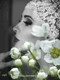 A Black And White Photo Of A Woman Wearing A Hat And Flowers . GIF