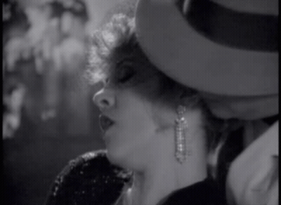 A Black And White Photo Of A Woman Wearing A Hat GIF