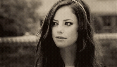 A Black And White Photo Of A Woman Wearing A Headband And Looking At The Camera . GIF